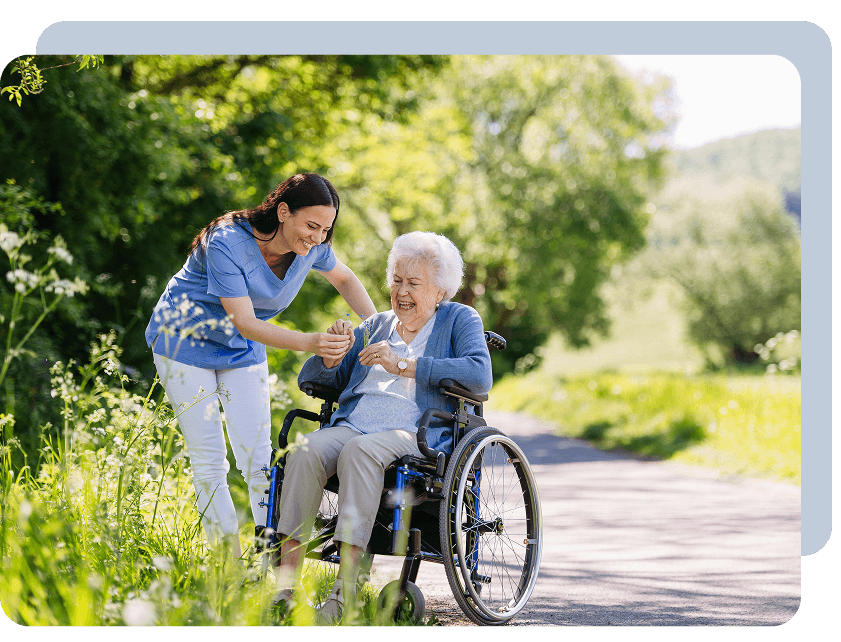Caregiver assisting elderly woman outdoors